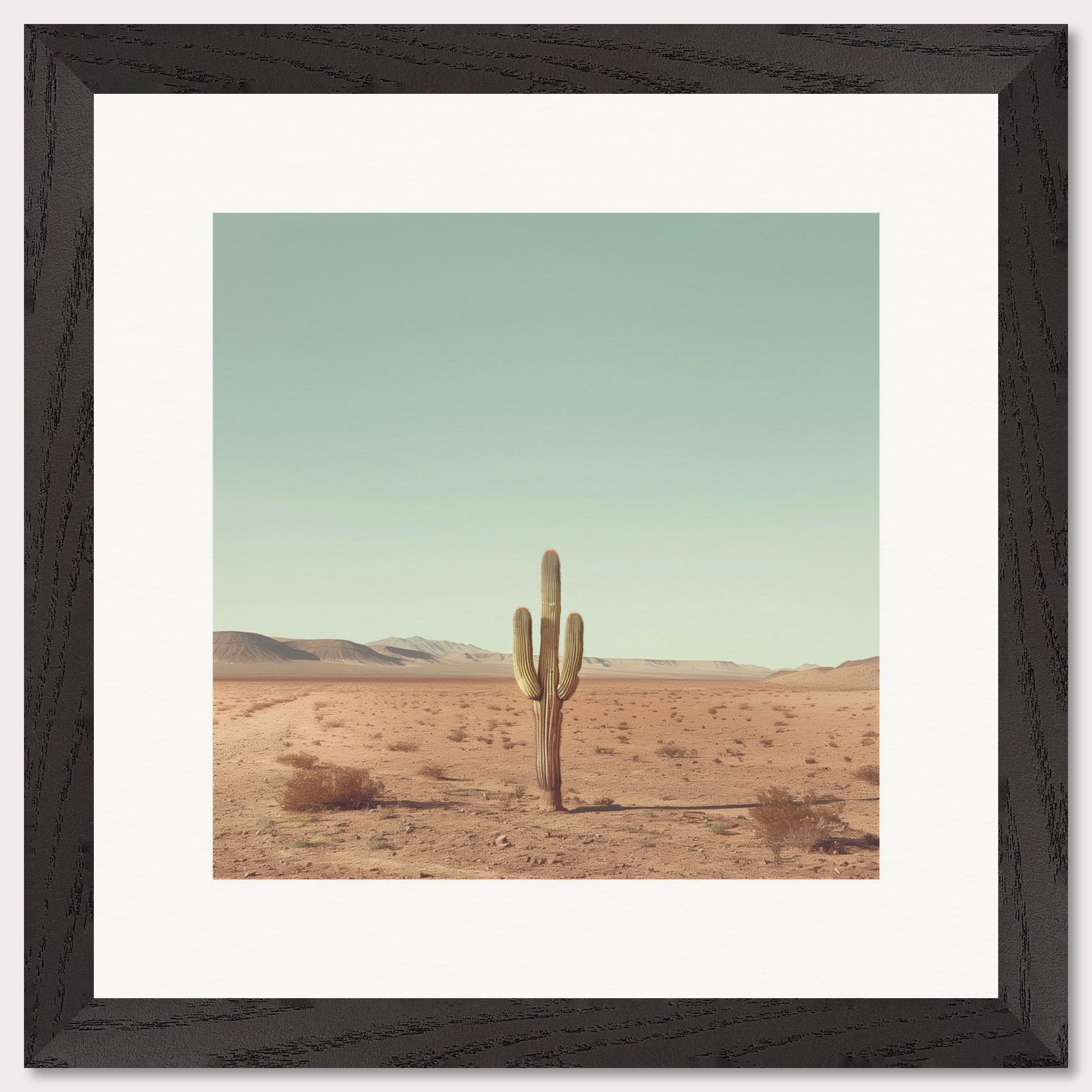 This serene photograph captures the solitary beauty of a lone cactus standing tall in a vast desert landscape. The clear blue sky stretches endlessly above, while distant mountains create a tranquil backdrop. The image is framed in a simple, elegant black border, enhancing its minimalist appeal.