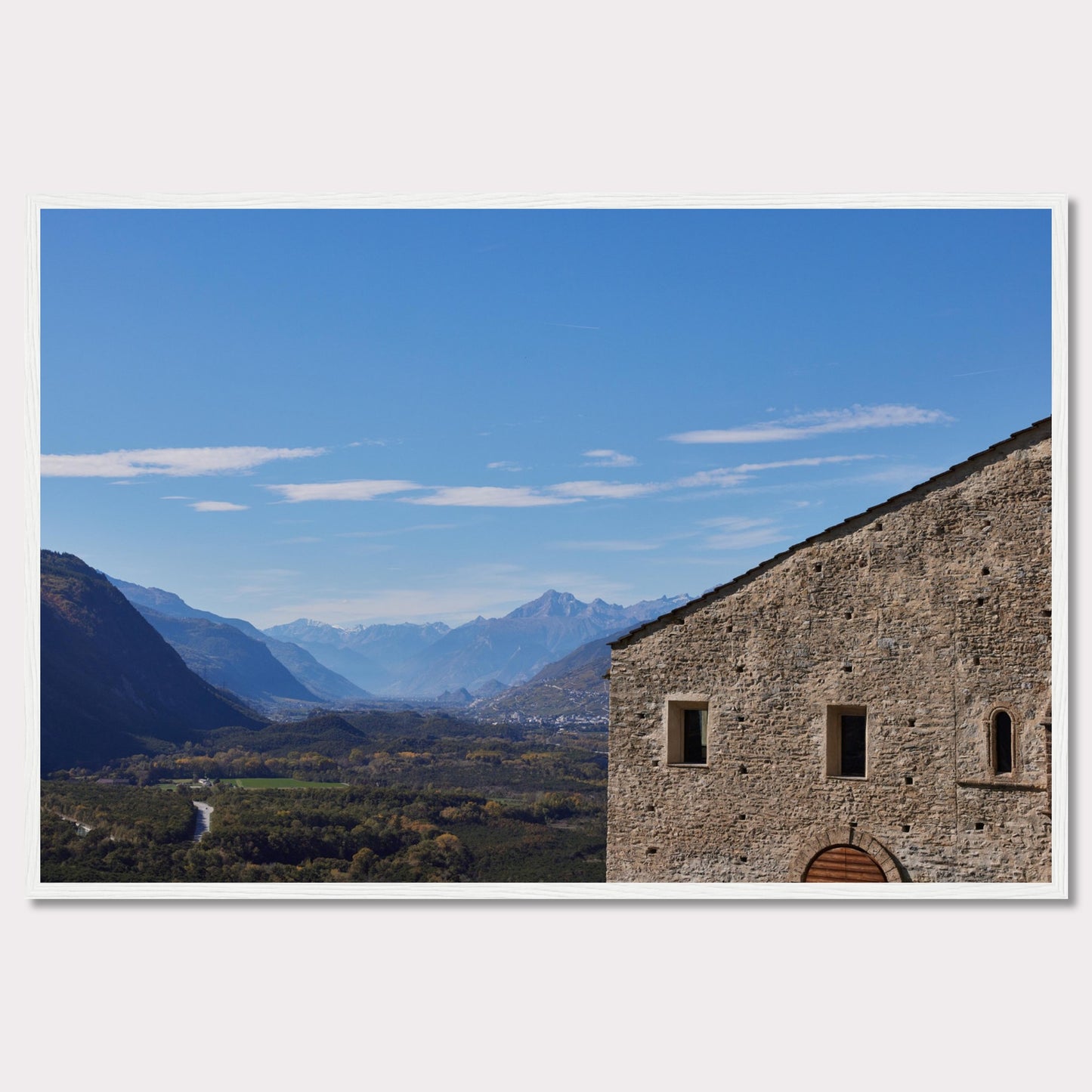 This stunning photograph captures a serene landscape with a historic stone building in the foreground and majestic mountains in the background.