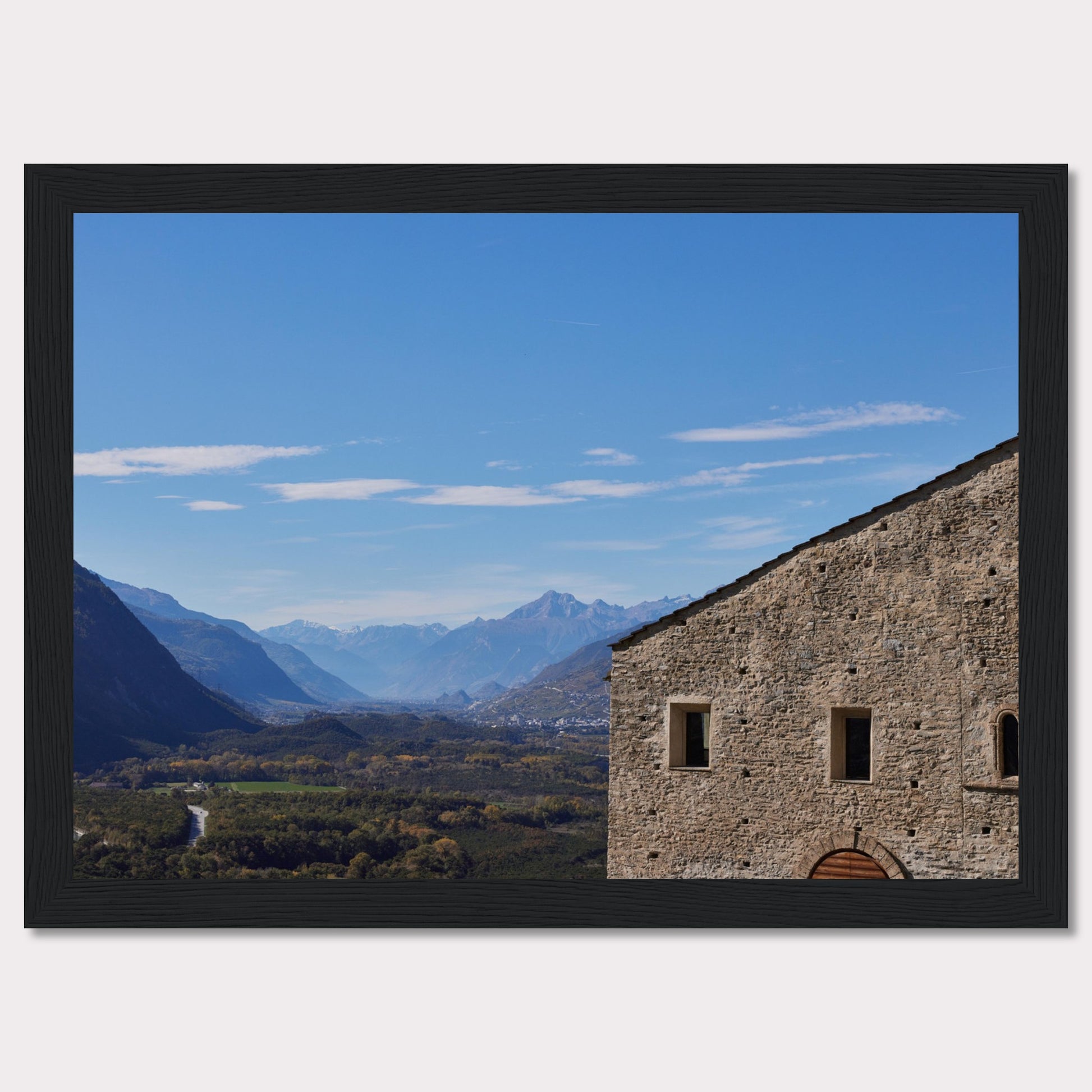 This stunning photograph captures a serene landscape with a historic stone building in the foreground and majestic mountains in the background.