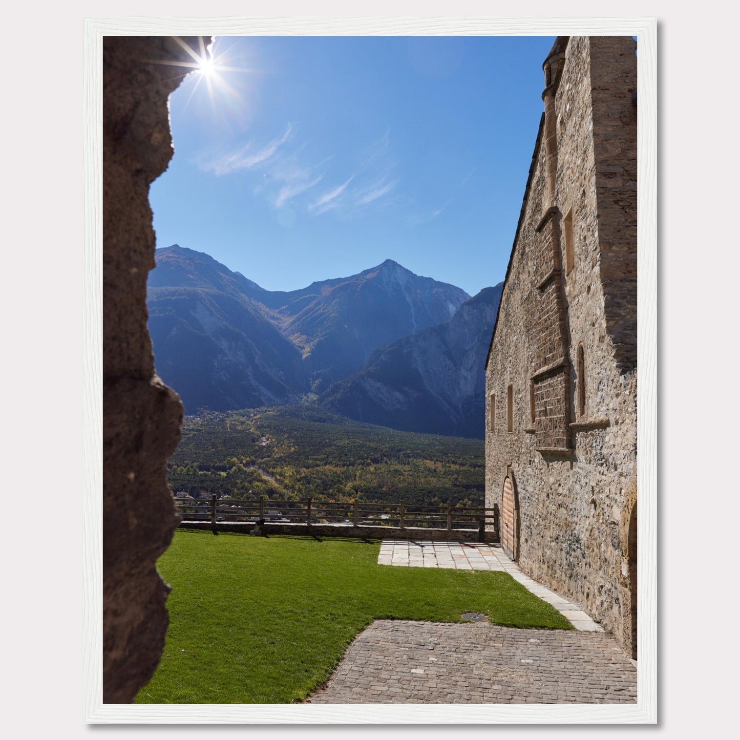 This captivating image showcases a stunning view of a mountainous landscape framed by the rustic stone walls of an ancient structure. The bright sun shines above, casting a warm glow over the scene.