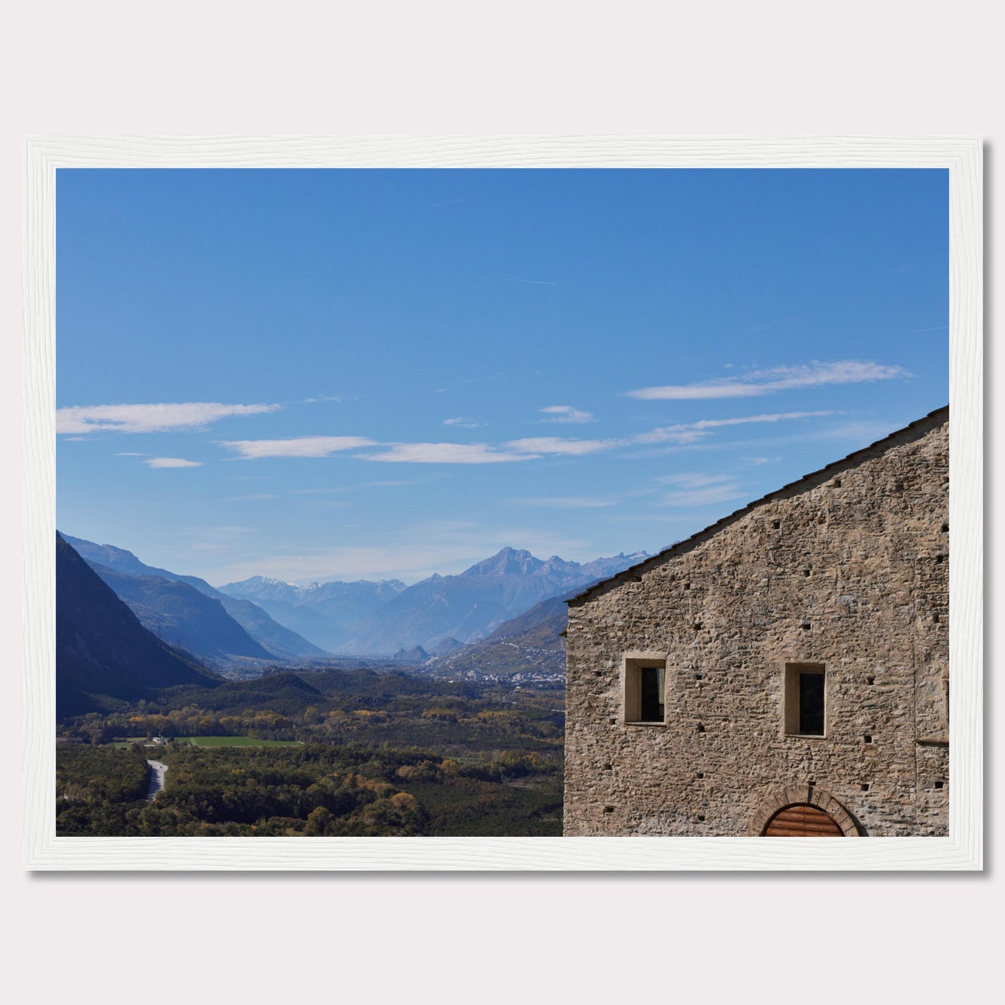 This stunning photograph captures a serene landscape with a historic stone building in the foreground and majestic mountains in the background.