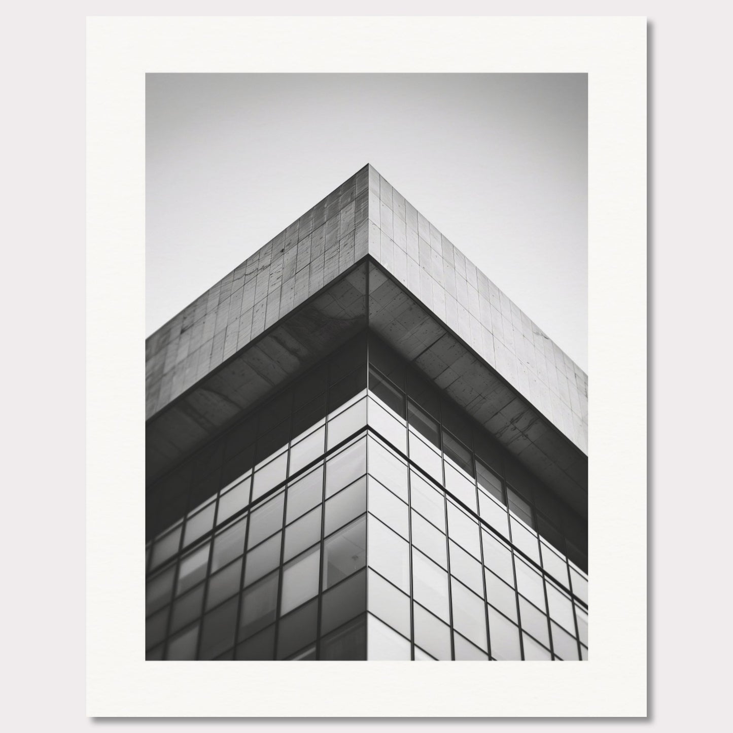 This striking black and white photograph captures the sharp, geometric lines of a modern architectural structure. The image focuses on the corner of a building, emphasizing its sleek glass windows and concrete elements.