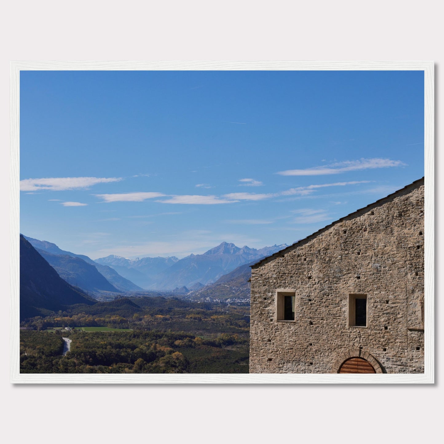 This stunning photograph captures a serene landscape with a historic stone building in the foreground and majestic mountains in the background.