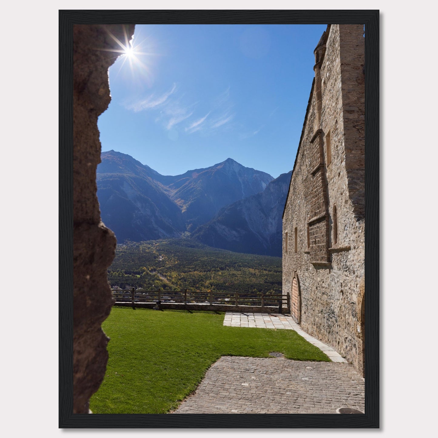 This captivating image showcases a stunning view of a mountainous landscape framed by the rustic stone walls of an ancient structure. The bright sun shines above, casting a warm glow over the scene.